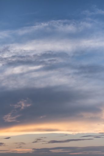 A vertical low angle shot of the breathtaking clouds in the colorful sky captured at sunset