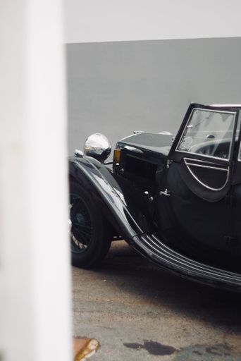 A vertical shot of a vintage black car parked in the street