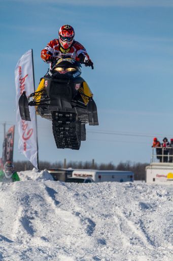 snowmobiler competing in extreme sports. Snowmobiler jumping high above the track. On a snowmobile, a sportsman. It's a sunny day for a winter