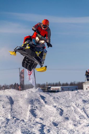 snowmobiler competing in extreme sports. Snowmobiler jumping high above the track. On a snowmobile, a sportsman. It's a sunny day for a winter