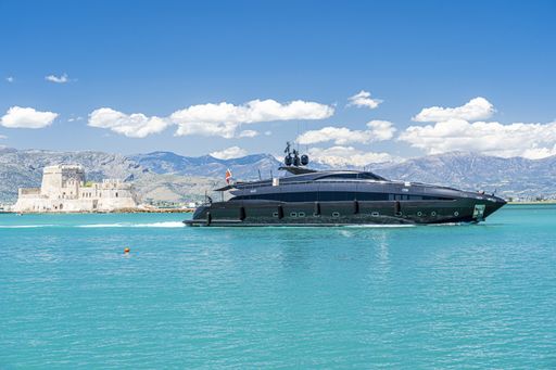 The image shows a view of a portion of the harbor at Nafplion with a beautiful yacht in the foreground and a fortress on an island in the background