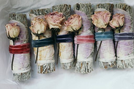 An overhead shot of beautifully arrange smudge sticks on white wrapping paper