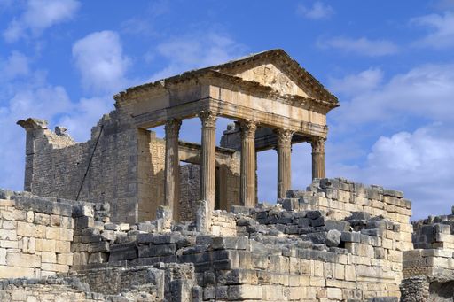 The capitol at the Roman ruins in Dougga, Tunisia, North Africa against a blue cloudy sky