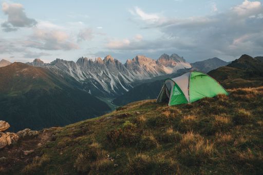 A beautiful shot of a green tent at the top of a mountainous landscape