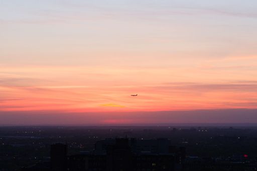 An airplane flying in beautiful sunset sky over the dusky cityscape