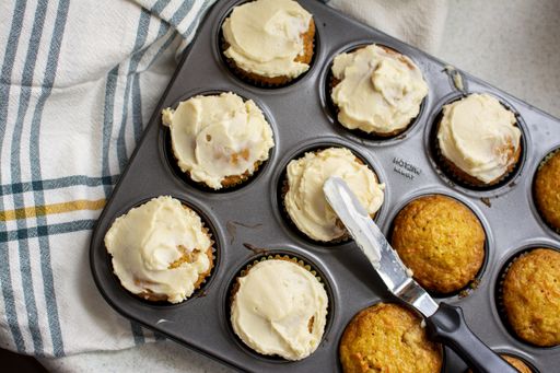 An overhead shot of baked muffins with cream in a gray muffin tray