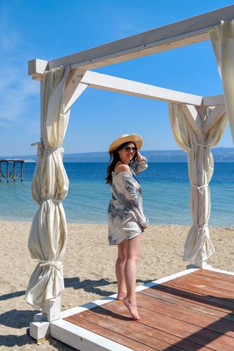 Full length photo of young woman standing on pavilion deck on sandy beach in summer