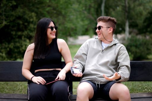 Two friends having fun in a bench of a big park