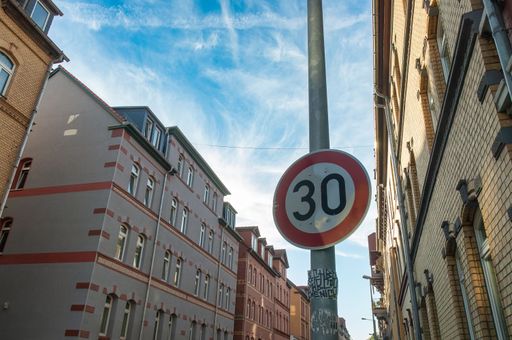 A low angle shot of a speed limit sign on a metallic post against buildings in Jena, Germany