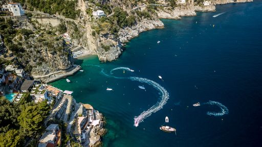 An aerial view of the blue sea against rocky Amalfi coast covered with greenery and buildings in Italy