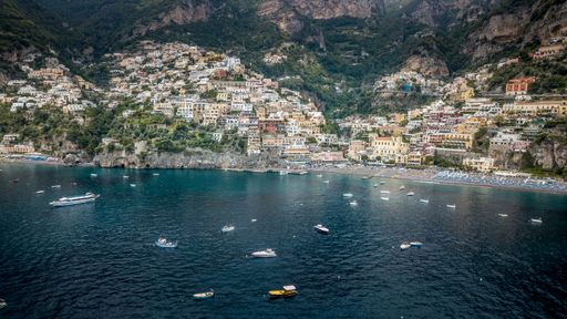 An aerial view of the blue sea against rocky Amalfi coast covered with greenery and buildings in Italy