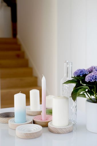 A vertical shot of a home decor of five candles a glass bottle and flowers. Great for a home decor piece