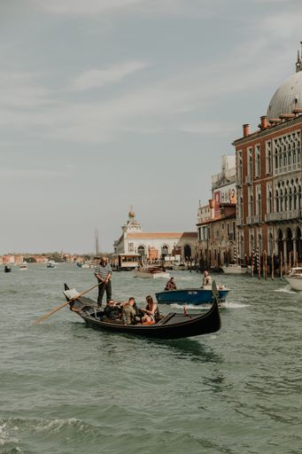 A vertical shot of a gondolier on a gondola sailing in a canal in Venice, Italy
