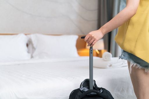 A closeup shot of a female holding a suitcase standing in the hotel room - a traveling concept