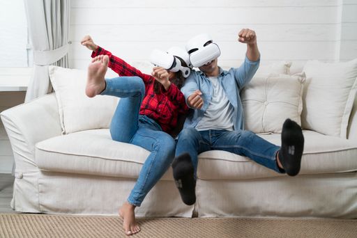 A happy couple in VR headsets enjoying a virtual reality experience in their house