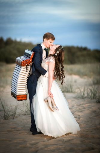 A vertical shot of a happy Caucasian newly married couple kissing on the beach on their wedding day