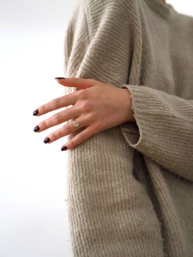 A young woman wearing a beige sweater against a white background