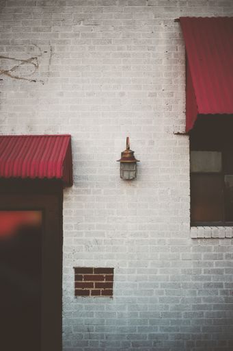 A vertical shot of a cute white brick building with red canopies and a metallic lantern in Dallas US