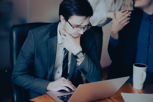 Young serious  professional business man, focused male student wearing glasses working on laptop
