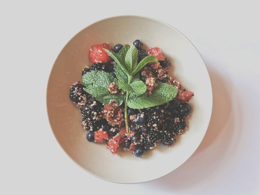 A closeup top view of a delicious berry salad with a leaf in a bowl