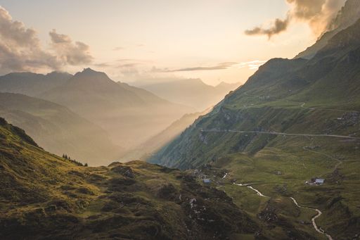A aerial shot of misty green grass mountains during a sunset