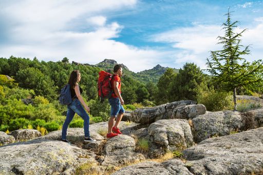 A traveler couple standing together on the rocks at the mountains over the blue sky background