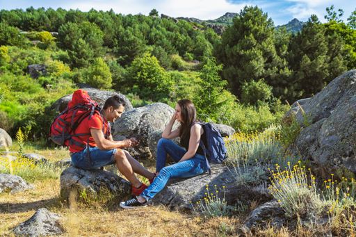 A beautiful shot of a happy couple sitting on the rock while enjoying the fresh air