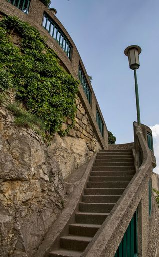 A vertical shot of an old staircase by a rocky wall