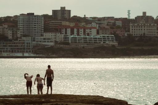 An eye-level shot of friends jumping to dive into the sea in Bondi beach, Sydney, Australia
