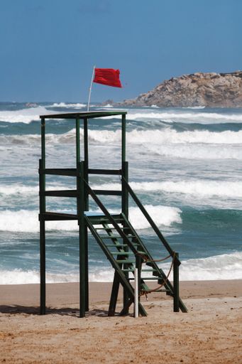 A vertical shot of an empty lifeguard post near the seashore