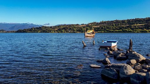 A wooden boat sailing on a river under a blue sky