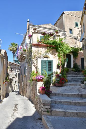 A vertical shot of narrow street between the old houses of Modica, a historical town in Sicily, Italy
