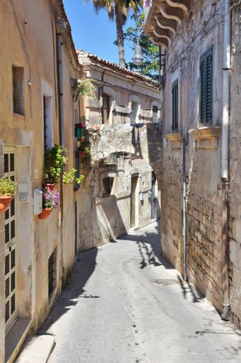 A vertical shot of narrow street between the old houses of Modica, a historical town in Sicily, Italy