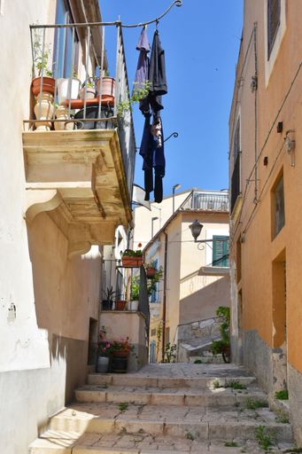 A vertical shot of narrow street between the old houses of Modica, a historical town in Sicily, Italy