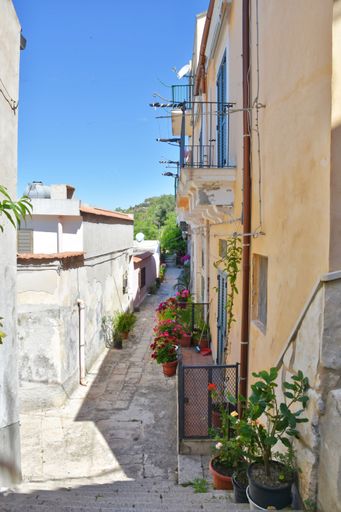 A vertical shot of narrow street between the old houses of Modica, a historical town in Sicily, Italy