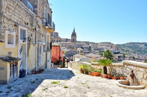 A vertical shot of narrow street between the old houses of Modica, a historical town in Sicily, Italy