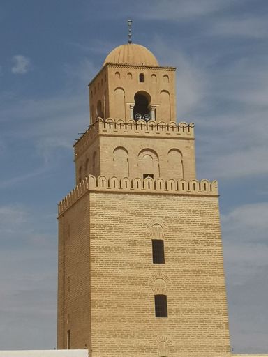 A beautiful vertical view of an old mosque against blue sky in Tunisia, Africa