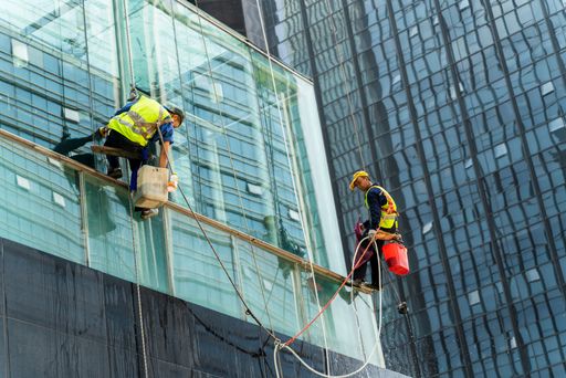 Chongqing, China-July 20th, 2021: chinese worker cleaning windows service on high rise building exterior.