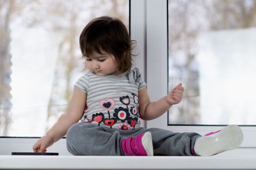 A close up of a cute little girl with phones trying to make a call, showing the phone and playing with