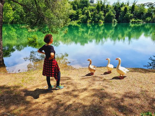 A woman standing in front of geese and a beautiful lake of Penne in Abruzzo, Italy