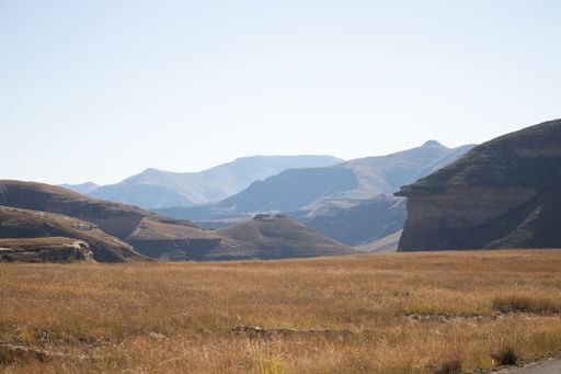A top view of large brown valley surrounded by rocky mountains against clear sky