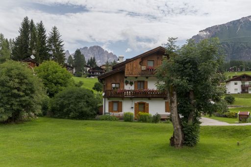A scenic view of a wooden cottage surrounded by greenery in Cortina d'Ampezzo, Italy