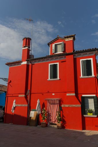 A vertical shot of a beautiful red building along the street of Venice in Italy during the daytime