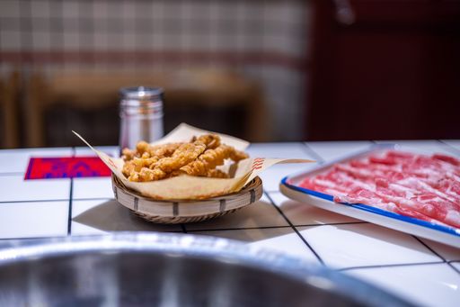 A closeup shot of a fried food on a white table next to a plate of meet in China