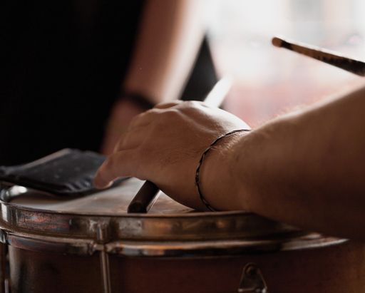 A white man playing timbales with blurred background