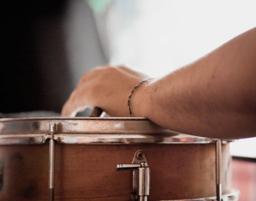 A white man playing timbales with blurred background