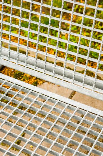 A closeup shot of a white metal bench in a park during the daytime