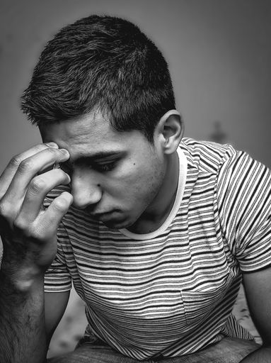 A vertical shot of an upset young male in grayscale