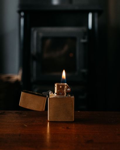 A vertical selective focus shot of a lit lighter on a wooden table
