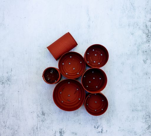 A high angle view of red cans in different sizes with holes on the table